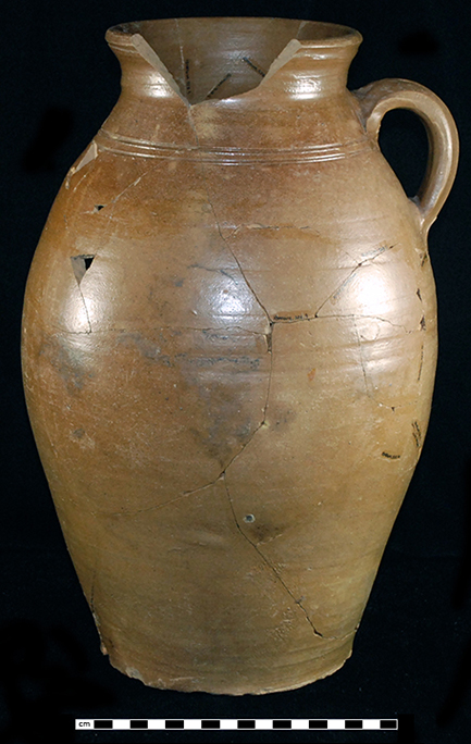 Buff bodied salt glaze stoneware handled jar with incised parallel lines on shoulder. Iron wash on interior and exterior.  Strap handle. Three gallon capacity. Vessel height: 15.00”, Vessel rim diameter: 5.75”, Vessel base diameter:  6.00”, Vessel V-19 from 18MO609.